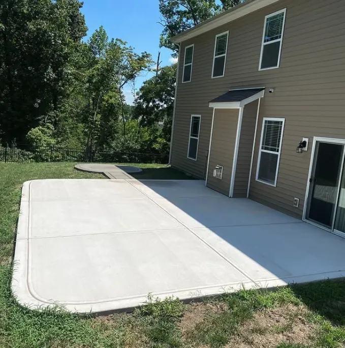 Concrete patio with a curved edge beside a home